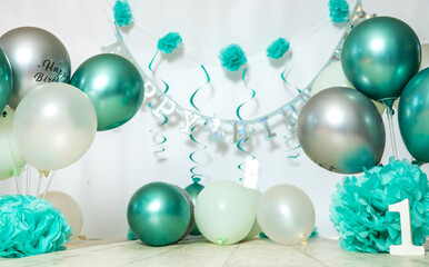 sliver, blue and white decoration for a 1st birthday cake smash studio photo shoot with balloons, paper decor, cake and topper