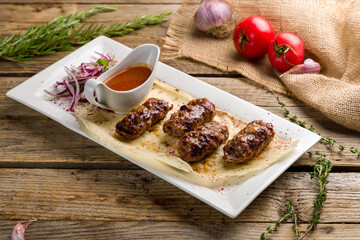 khan kebab with red onion and tomato sause on old wooden table