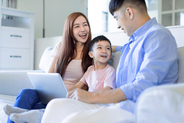 young happy cheerful family  resting on sofa in living room using  the laptop