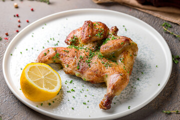 fried chicken tobacco with sliced green onion and lemon on plate macro close up