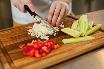 The cook cuts vegetables with a knife to prepare the dish. Cutting vegetables.
