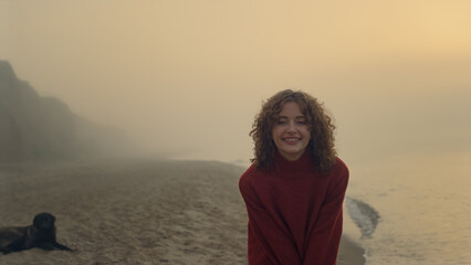Smiling woman posing on beach at sunrise. Casual girl with happy face expression