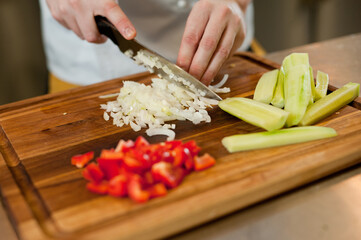 The cook cuts vegetables with a knife to prepare the dish. Cutting vegetables.