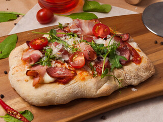 pizza with bacon and Bavarian sausages, tomatoes and parmesan cheese