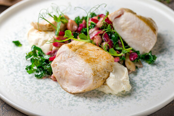 Sliced Grilled chicken Breasts with garnish on plate on brown table macro close up
