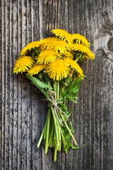 Bouquet of dandelion flowers, yellow wildflowers on the background of an old board