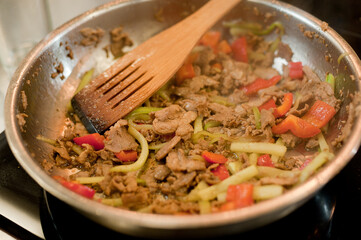 Cook fries meat in a pan with vegetables.