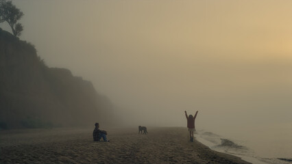 Cheerful couple spending vacation on beach. Playful woman running on sea shore