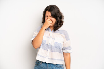 hispanic pretty woman feeling disgusted, holding nose to avoid smelling a foul and unpleasant stench