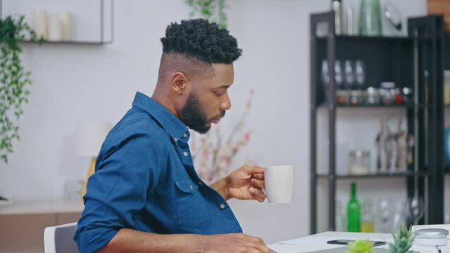 Black young man opening laptop and starting work on project, freelance job