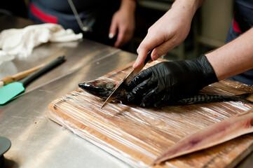 Fototapeta na wymiar The cook separates the fillet from the fish and clears it from the bones. Mackerel fillets.