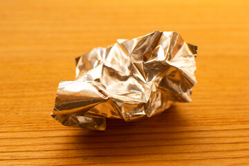 aluminum foil wrap without chocolate candy on a wooden background. Texture of used crumpled...