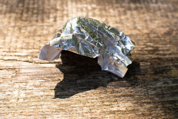 aluminum foil wrap without chocolate candy on a wooden background. Texture of used crumpled...