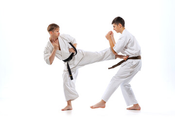 Two athletes, karate-do fighters in doboks practicing karate isolated on white background. Concept of sport, education, skills, martial arts, healthy lifestyle © master1305