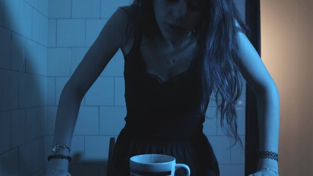 Young alienated woman staring at the tea bag he is playing with. 