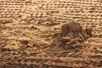 Small pile of sand with wave patterns and tire tracks on Blackpool beach at sunset.