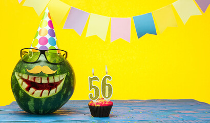 Funny watermelon in festive garlands for happy birthday greetings funny. Copy space watermelon with smile character. Happy birthday with number 56 - obrazy, fototapety, plakaty