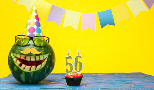 Funny watermelon in festive garlands for happy birthday greetings funny. Copy space watermelon with smile character. Happy birthday with number 56
