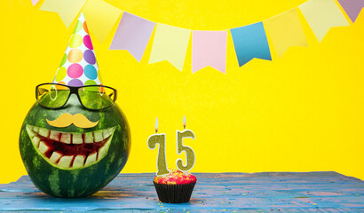 Funny watermelon in festive garlands for happy birthday greetings funny. Copy space watermelon with smile character. Happy birthday with number 75