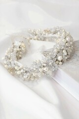 Soft selective focus image of bridal crystal and pearl handmade hairband on white silk light background. Wedding concept