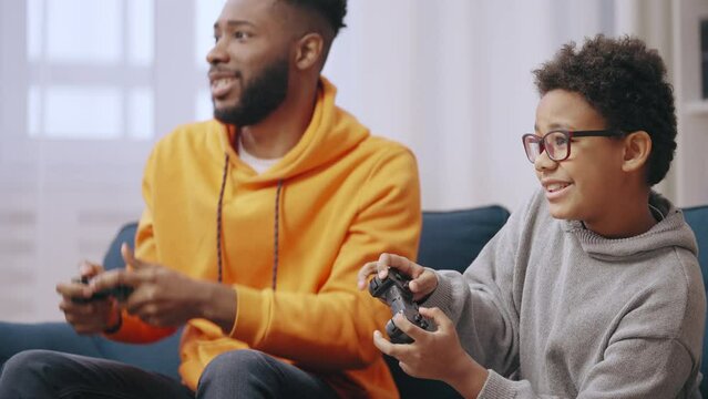 Happy young man playing video games with little brother, family having fun