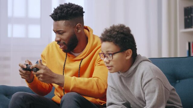 Cheerful big and little brothers enjoying video game together, giving high five