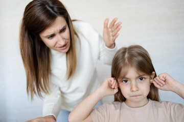 Daughter closing ears while mother scolding her.