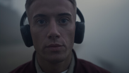 Handsome guy listening music in headphones. Closeup focused man posing at camera