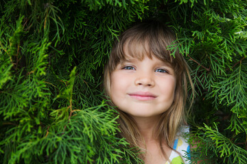 Relaxed child girl in thuja branches breathing fresh air with green branches in background. Aromatherapy and Spa concept. ecology. Earth Day. climate change