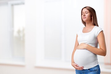 Happy expectant mother feeling kicks, caressing big belly. Pregnant woman. Motherhood, pregnancy concept