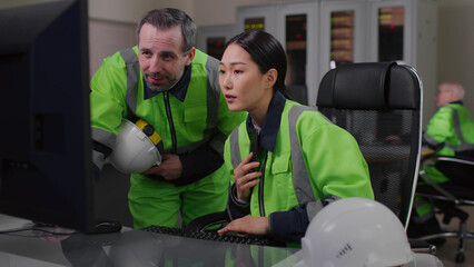 Asian woman technician discuss data on computer screen with foreman