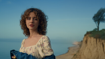 Obraz premium Dreamy girl standing alone on sand beach close up. Portrait of beautiful woman.