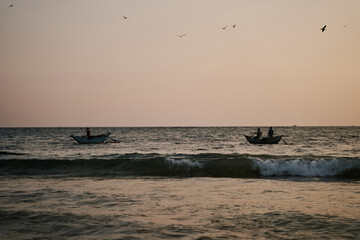 Fototapeta premium Two boats with fishermen in the ocean at sunset in Sri Lanka