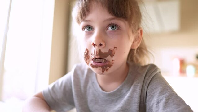 children eat chocolate. dirty little baby kids in the kitchen eating chocolate in the morning. happy family eating sweets kid dream concept. lifestyle baby dirty face eating chocolate cocoa