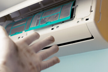 The worker points with a dirty hand at the indoor unit of the air conditioner. The concept of climate system maintenance