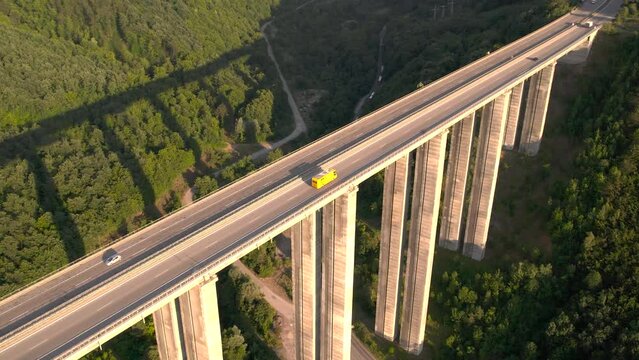 Aerial view of yellow truck or bus driving slowly on highway viaduct bridge