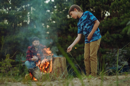 Father and son sitting by fireplace. Camping concept. Image with selective focus