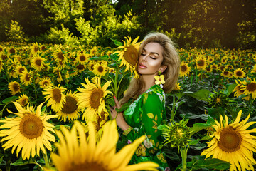 Beautiful young woman in a field of sunflowers. Happy female model is holding sunflower in Sunflowers field. Natural beauty.