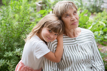 grandmother and little granddaughte hag and having fun together in the garden. Happy family enjoying summer outdoors.