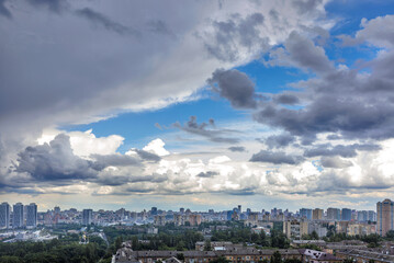Thunderclouds fill the blue sky above the city.