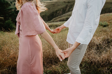 Beautiful woman and man are hugging and kissing on the field at sunset. A young couple hugging and kissing on a field at sunset.