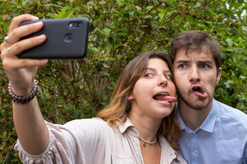 un couple d'amis fait un selfie. Ils se prennent en photo avec un téléphone en riant et en faisant des grimaces