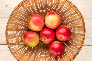 Several juicy red apples in a basket on a wooden table, macro, top view.
