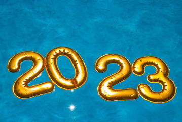 figures 2023 new year float in the blue pool in splashes of water