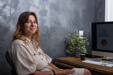 Jolie jeune femme de 25 ans qui travaille à la maison sur un ordinateur. Elle est en train de rire.