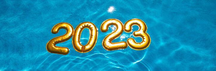 banner figures 2023 new year float in the blue pool in splashes of water