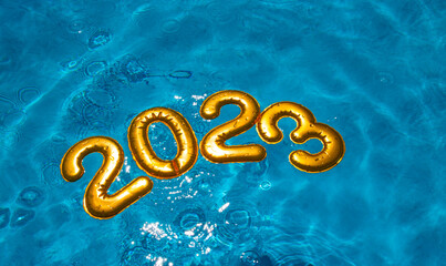 figures 2023 new year float in the blue pool in splashes of water