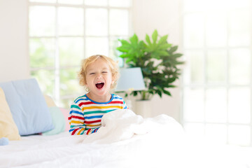 Child playing in bed. Kids room. Baby boy at home.