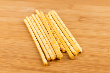 Yellow corn snack sticks side view on a wood cutting board