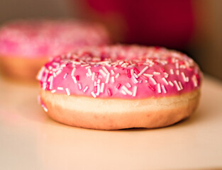 pink donut closeup blurred background, focus in the foreground.